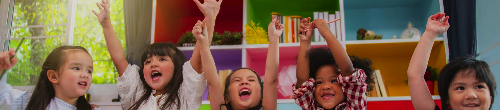 Happy Kids Raising Hands at a Preschool